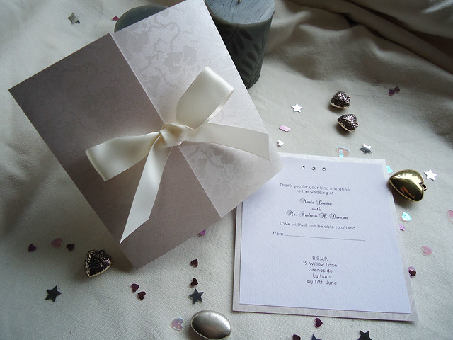 A gatefold wedding invitation and reply card. The gatefold is held together