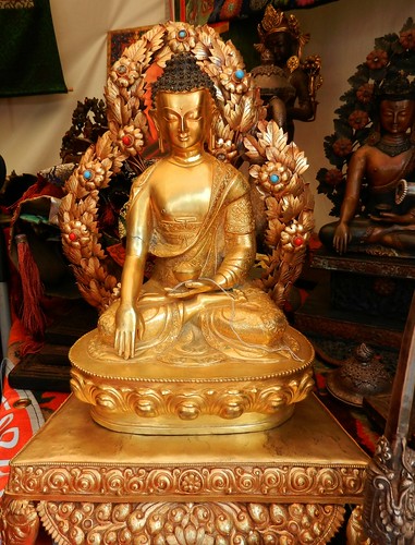 Ornate brass statue of Lord Buddha in the earth touching mudra surrounded by leaves, webbed fingers, lotus and wish fulfilling jewels ornaments, another similar statue behind, Tibetan goods for sale, tent, Kalachakra for World Peace, Washington D.C., USA by Wonderlane