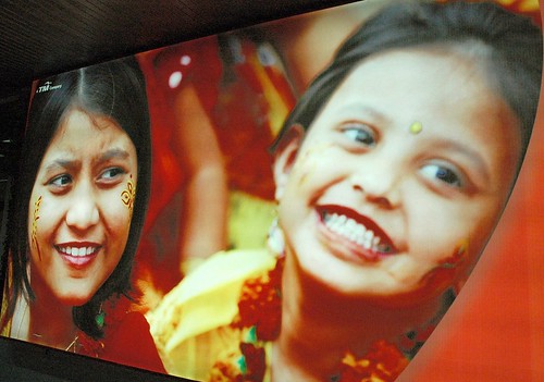 Henna painted on two smiling girls, red, photo advertisment promoting tourism, airport, Dhaka, Bangladesh by Wonderlane
