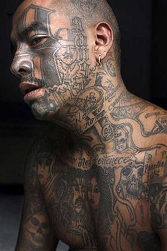 Smoking with facial tattoos that reference the Mara gang