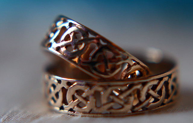 close up of wedding rings with hint of colour in the background