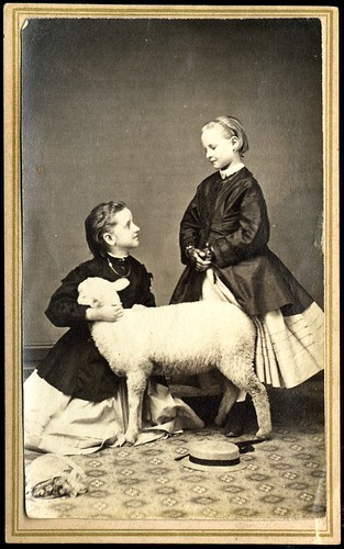 Two girls posed in studio with lamb