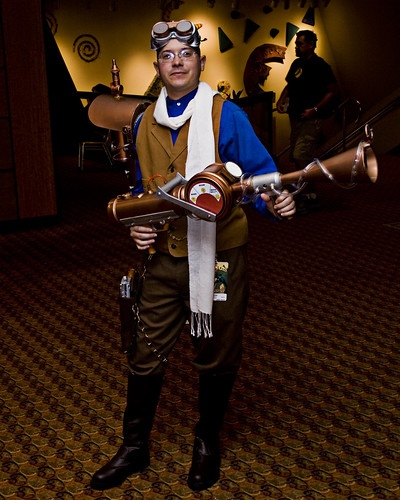A steampunk guy holding a giant fake weapon