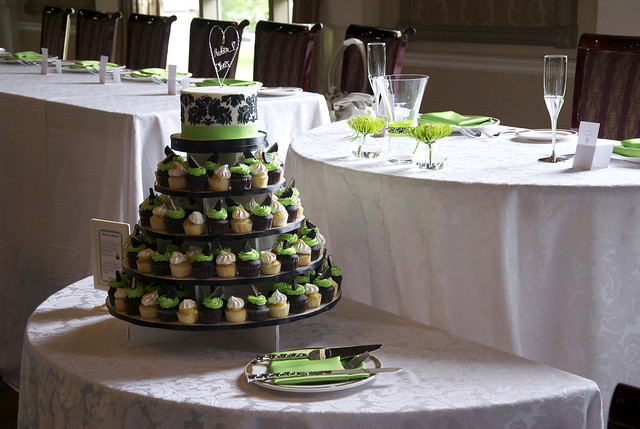 A black and white damask wedding cake atop a tower of cupcakes with apple 