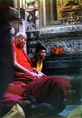 His Holiness Dilgo Khyentse Rinpoche at the Mahabodhi Stupa, watching people prostrate, near the Bodhi Tree, sculptural decoration and gold on a statue, Bodhgaya, India, 1990, photo by Gary by Wonderlane