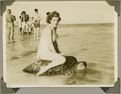 Young woman riding on the back of a turtle at Mon Repos Beach