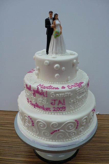 Iced wedding cake with writing and swirls with topper