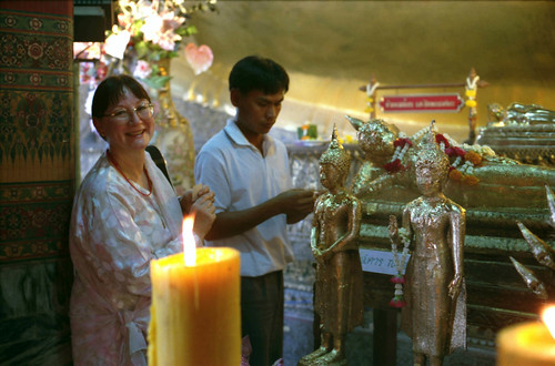 American Tibetan Buddhist sangha member, Diane, purchasing gold leaf to apply to statues of the Buddhas and Bodhisattvas as offerings, candles, statues covered with gold leaf, Bangkok temple, Thailand, Pilgrimage, 1993 by Wonderlane
