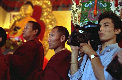 Prince Kenrab filming video, senior lamas, statue of Lord Buddha, Tibetan Buddhism, Sakya College, Rajapur, Uttar Pradesh, India in 1993 by Wonderlane