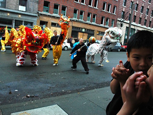 Two boys chat and keep their hands warm watching the New Years Dragon and Lions Dance, Seattle, Washington, USA by Wonderlane