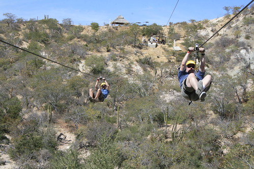 Two people zip lining through the desert