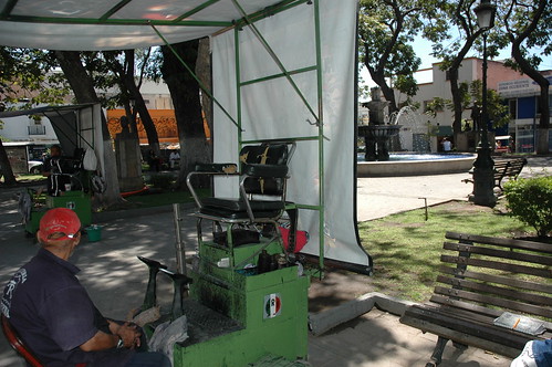 In use, a old green metal shoe shine chair, awning, public park, Guadalajara, Jalisco, Mexico by Wonderlane