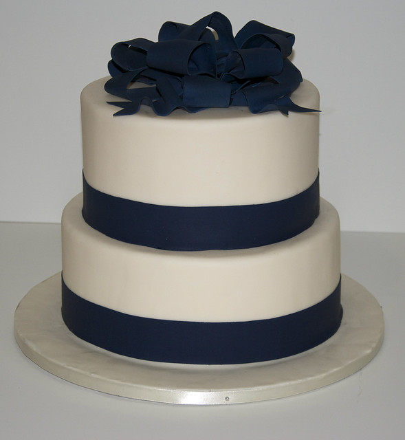 A simple 2 tier white fondant wedding cake with an edible navy blue ribbon