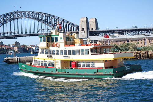 A wooden ferry boat under way heading towards the Harbour Bridge in Sydney's Port Jackson
