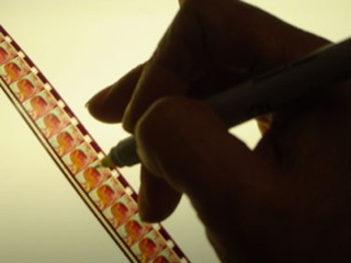 a hand painting a film strip frame by frame