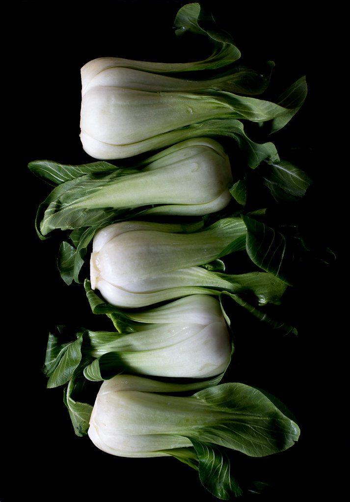 Still life of baby bok choy on black surface