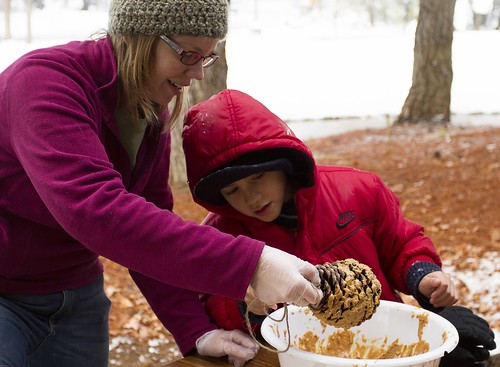 Ally Buccanero, Shasta College student and volunteer, demonstrates how to make a bird feeder using a large pine cone and peanut butter during Shasta-Trinity National Forest’s annual Operation Christmas Tree event on Dec. 7. (U.S. Forest Service)