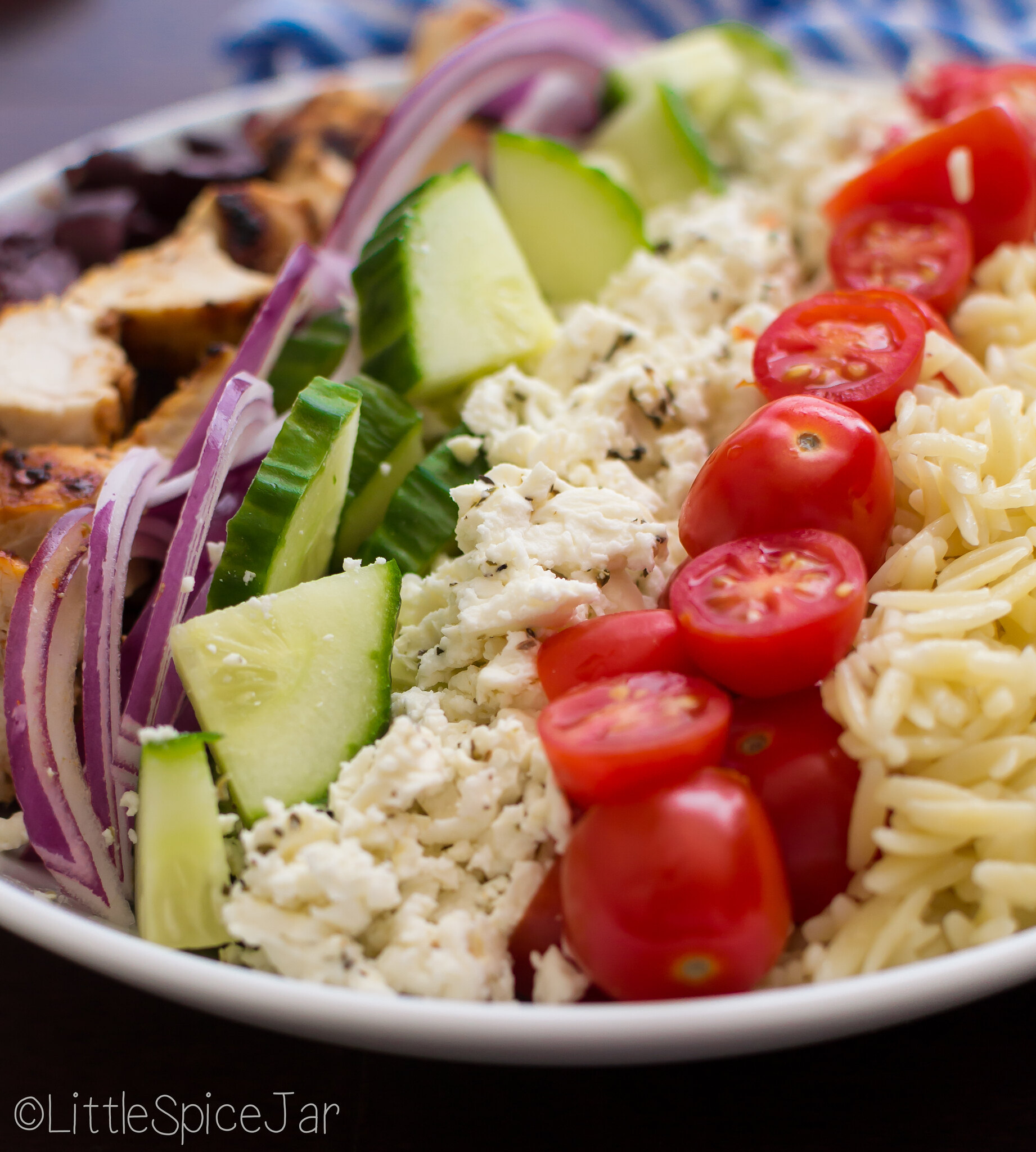 close up of orzo past salad plate with individual ingredients in a line