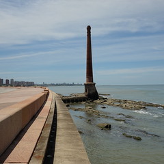 chimney on the shoreline rocks, with the promenade (pavement of the coastal road) alongside