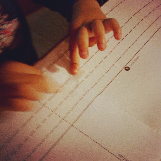 Little hands helping Mommy tape together her sewing pattern. #isew #mytoddlersews