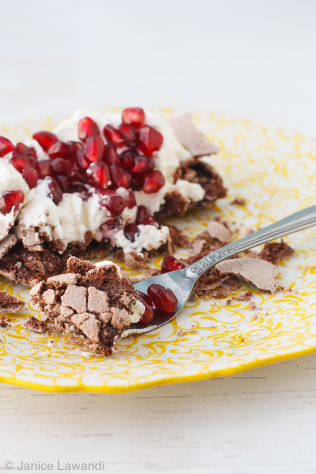 Mini chocolate pavlova with whipped cream and pomegranate seeds.