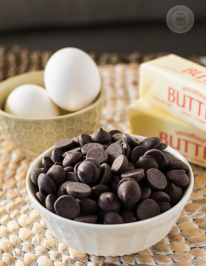 Chocolate Chips in a white bowl with sticks of butter and two white eggs in the background