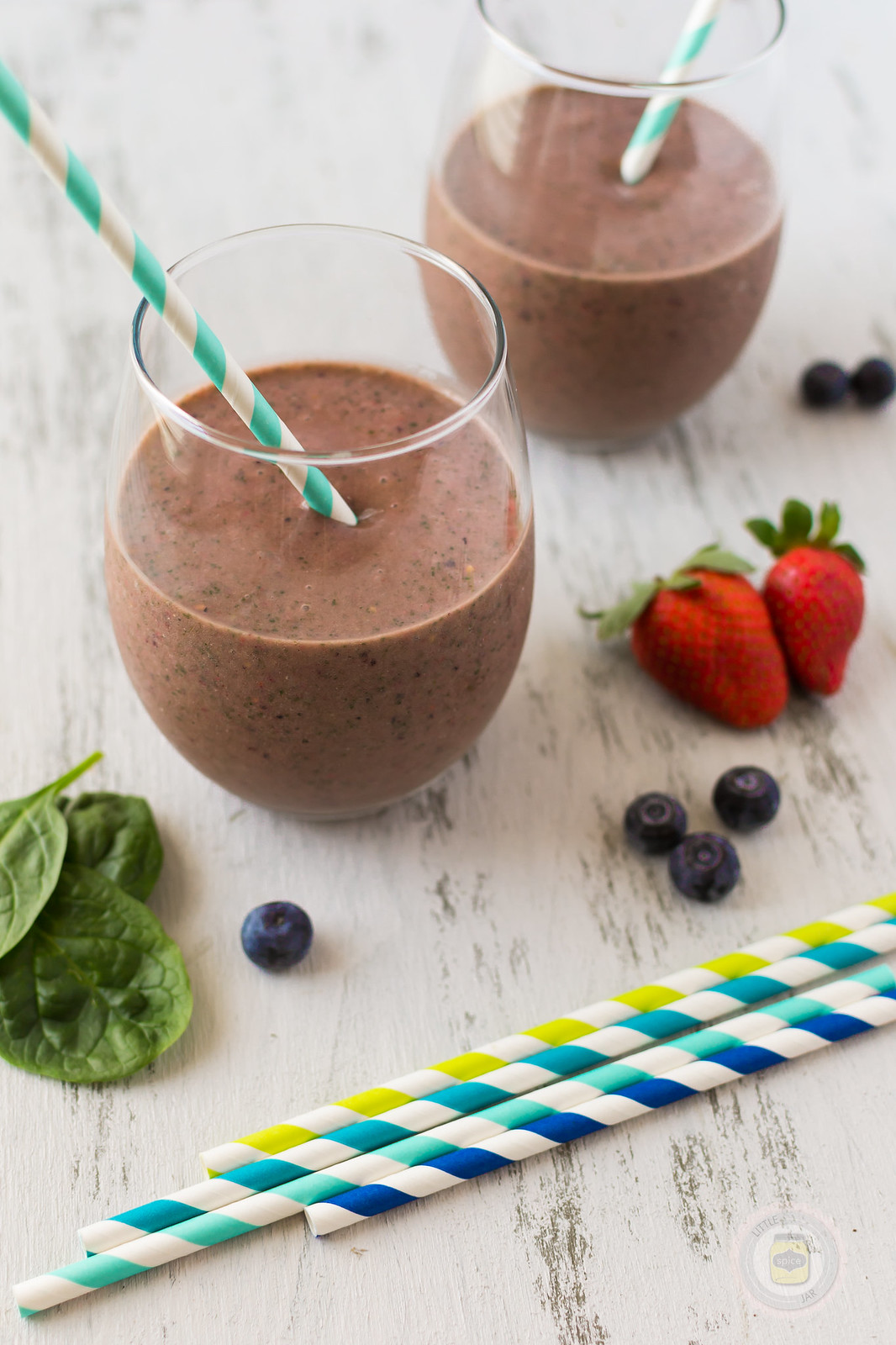 close up of smoothie glasses with straws and fresh berries on the side