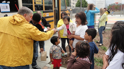Volunteers distribute sack lunches to children at the New Freedom Park Summer Food Service Program site in Aurora, Colorado.  The lunches are delivered in a school bus by an organization called Lunch Box Express.