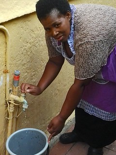 Queenie Magubane, 38, of Khayelitsha township in Cape Town, South Africa, uses a bucket to collect the water that constantly leaks from her outdoor tap. It is one of thousands of faulty taps across South Africa. Credit: Melany Bendix/IPS