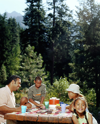 Father and mother sitting with son and daughter at picnic table. Photo courtesy of ThinkStock.