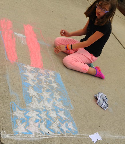 Ellie creating an American flag 3-d design on the 4th of July, colored chalk on concrete, eraser rag, West Olympia, Washington, USA by Wonderlane