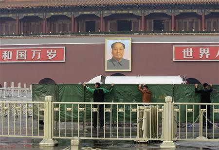 Policemen set up barriers in front of the giant portrait of the late Chinese chairman Mao as they clean up after a car accident at the Tiananmen Square in Beijing