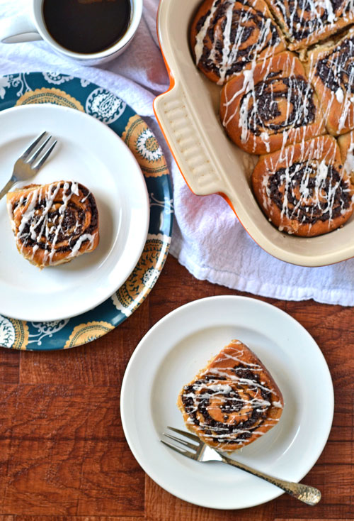 Chai-spiced chocolate cinnamon rolls in a baking dish and on two white plates with glaze