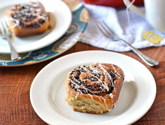 Two white plates with glazed sweet rolls filled with chocolate and chai spices