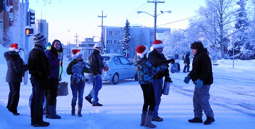 Community volunteers wearing Santa Claus hats - out to spred Christmas joy to the world - distributing hot cider, cookies, candy, and other goodies to passerbys, on a cold snowy day, Anchorage, Alaska, USA by Wonderlane