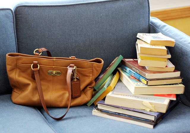 tan Coach purse and stack of books on blue coach