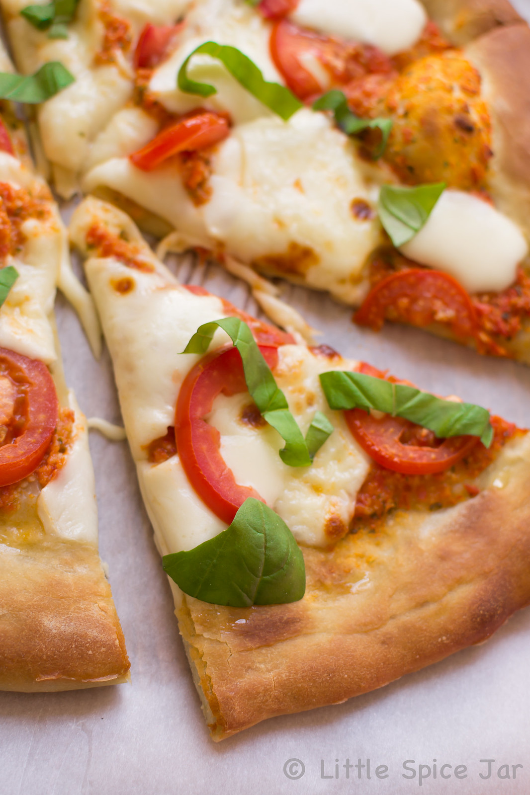 close up of a slice of Margherita Pizza with fresh basil and Roma tomatoes on top