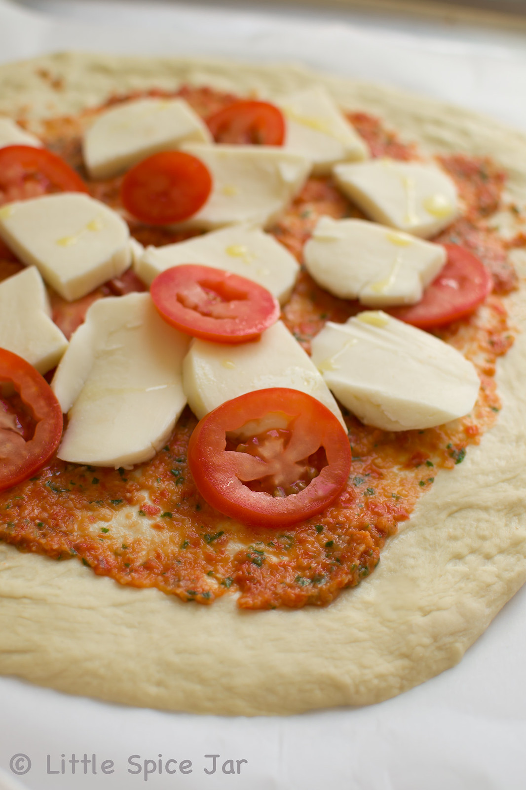 pizza dough toppe with sauce, sliced tomatoes and fresh slices of mozzarella cheese