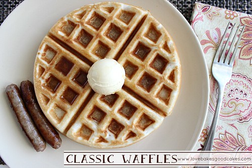 Classic Waffles on plate with sausage links, butter and fork.