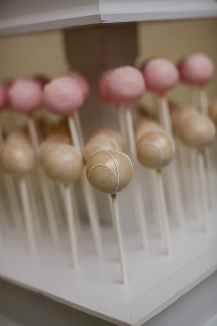 Gold shimmered cake pops with white drizzle and pastel pink with classic white nonpareils