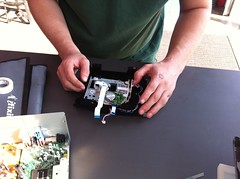 A set of hands working with a disassembled DVD player