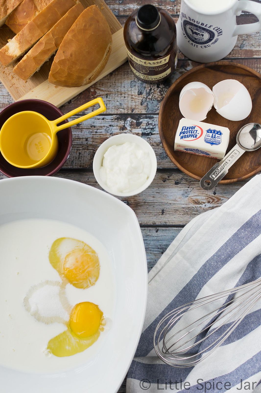 ingredients for French toast on surface with custard ingredients in large bowl