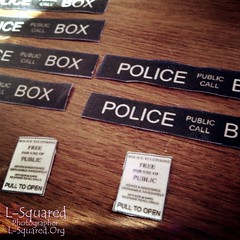 close ups of the black and white police public call box sign patches laying on a wooden surface. 