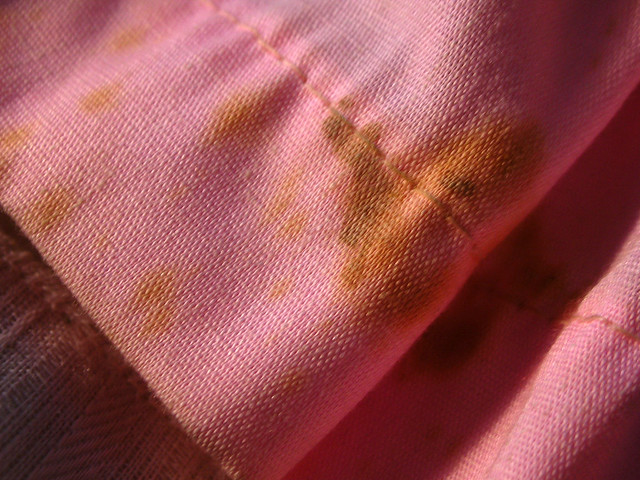 stained dress material on old doll