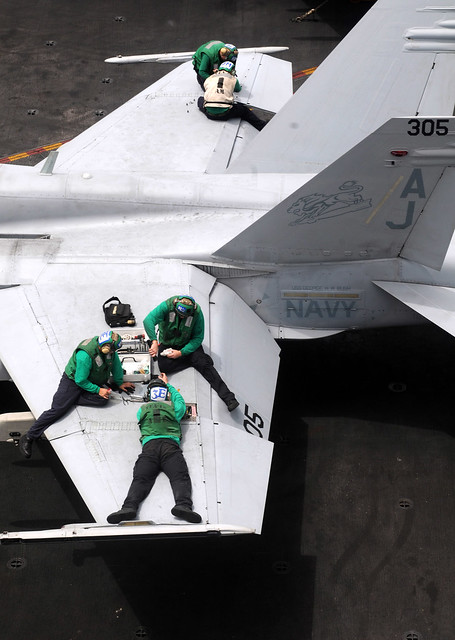Sailors perform maintenance on an F/A-18C Hornet aboard USS George H.W. Bush