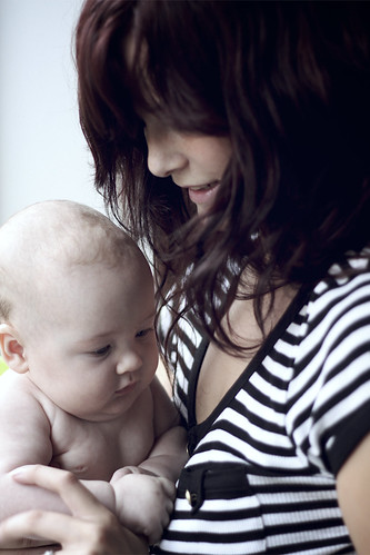 mamma di profilo con maglietta a righe bianche e nere che tiene in braccio in figlio neonato