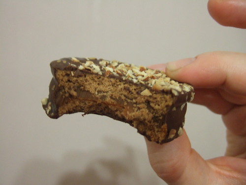 This alfajor is covered in chocolate and nuts.