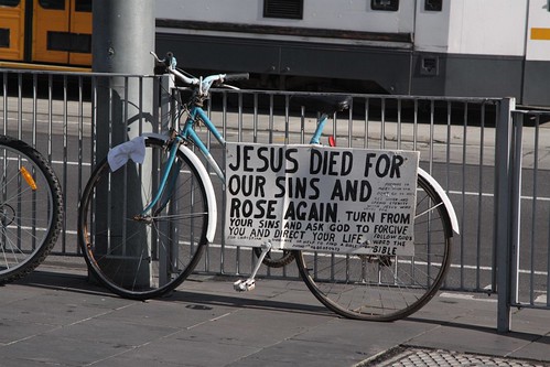 'Jesus died for our sins' poster tied to a parked bike at Federation Square