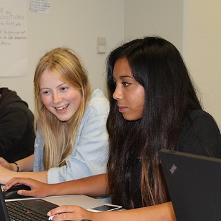 Two female students looking at a computer screen smiling. Photo by Kristina Hoeppner