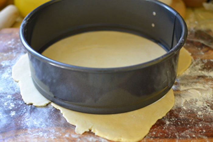 Take one dough-ball out of fridge (leaving others chilled until ready to use) and on a well-floured surface, roll to about 9 inches in diameter. If you have a round cheesecake pan or any 9-10 inch plate, use that as a guide to cut a circle and save the excess dough to use again.